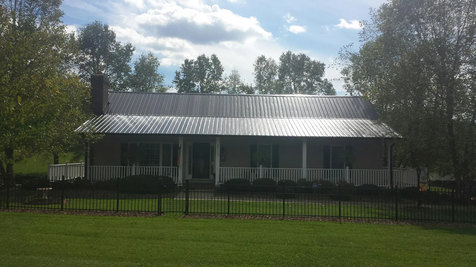 Gray metal roof on a brick ranch with a full width front porch — Gutter Guard Installation work by our crew in Aptos