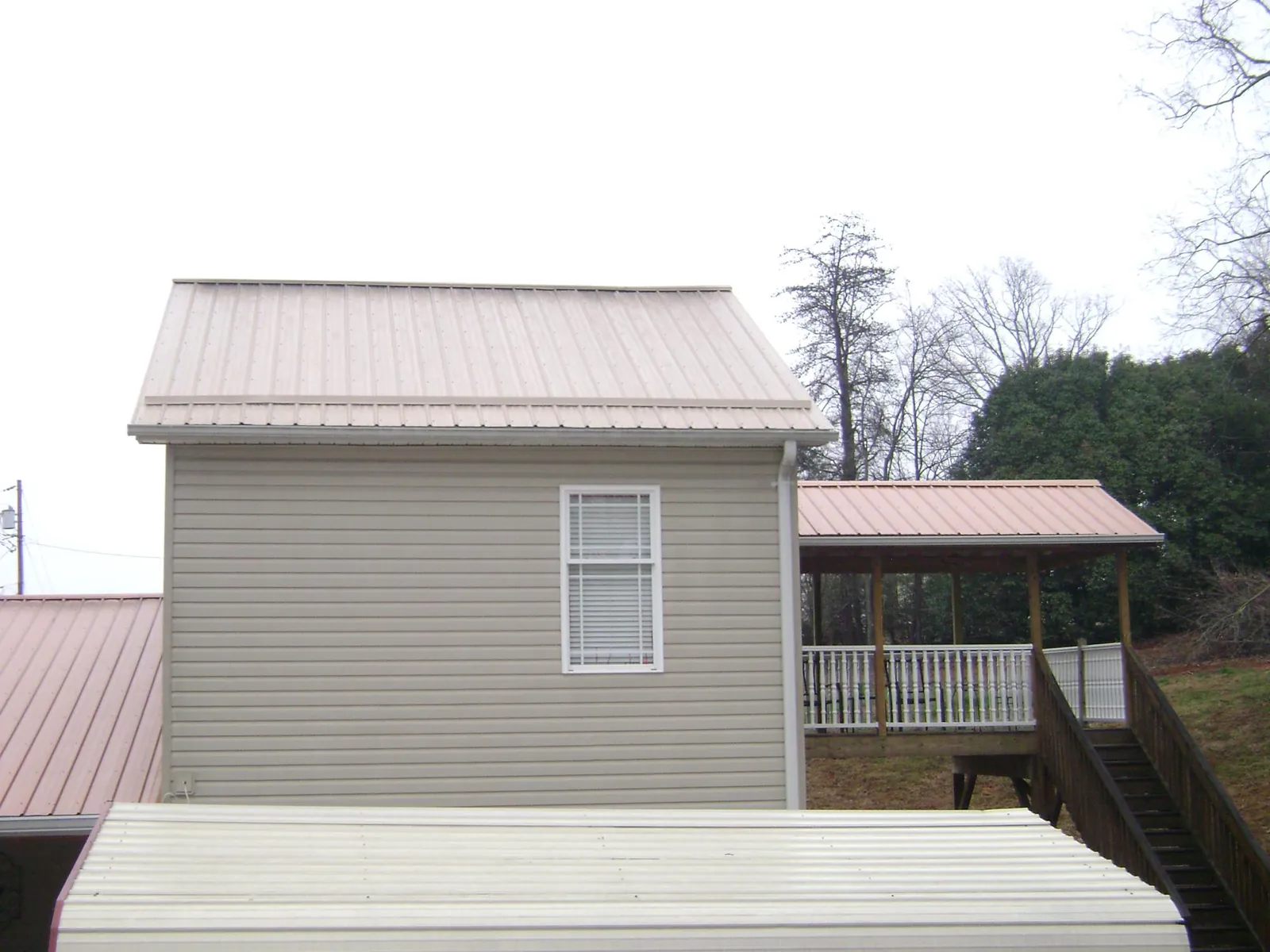 Tan metal roofs on a two story addition and attached porch, from a Roof Replacement job in Aptos